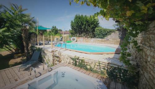 a swimming pool in a yard with a tub at Les chambres du Nid charentais in La Poterie