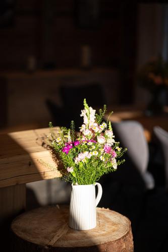 a white vase filled with flowers on a wooden table at Alpenloft Allgäu in Oy-Mittelberg