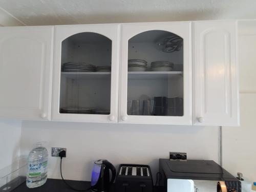 a kitchen with white cabinets with dishes in them at GATWICK Single ROOM in Ifield