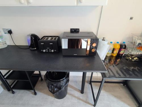 a black table with a microwave on top of it at GATWICK Single ROOM in Ifield