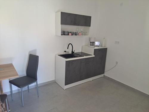 a small kitchen with a sink and a chair at Villa-Galliet in Buzsák