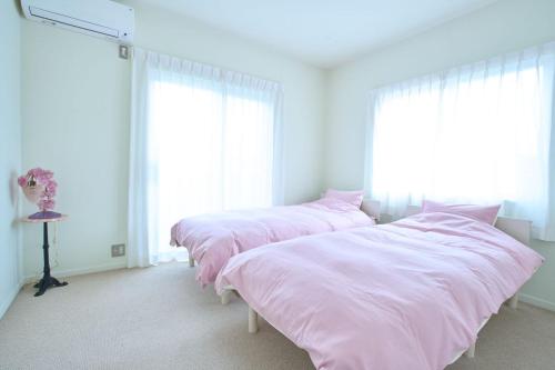 three beds in a room with pink sheets at 1日1組限定1棟貸し別荘 RivageBlue in Yawata