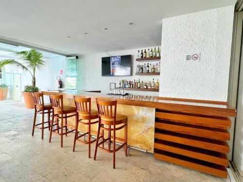 a bar with a row of wooden bar stools at Hotel Casa Mexicana Cozumel in Cozumel