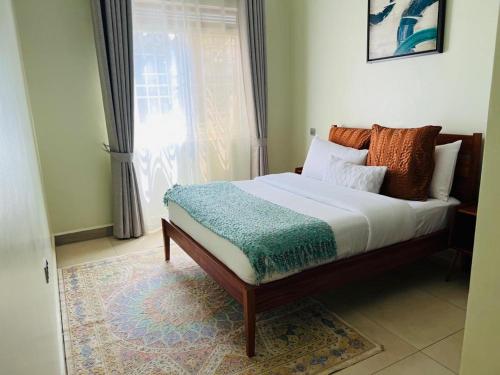 a bed sitting in a room with a window at Alsander Homes Peach in Bweyogerere