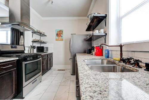 a kitchen with a sink and a stainless steel refrigerator at Howes Capitol I - Sleek & stylish walk to OU Med in Oklahoma City