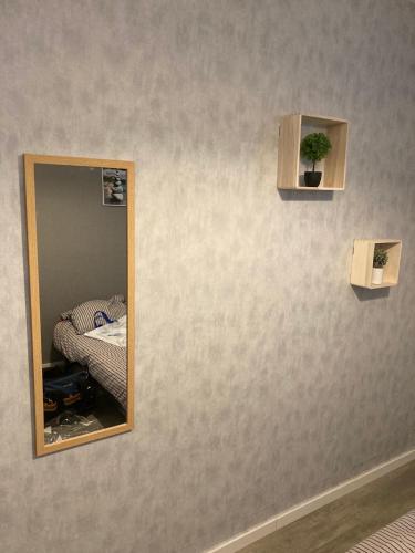 un miroir sur un mur avec un lit dans une chambre dans l'établissement Logement entier - 2 Chambres - Parking privé - 15 min Lyon et Aéroport, à Saint-Maurice-de-Beynost