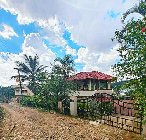 a house with a gate next to a dirt road at Nellakki Homestay in Madikeri