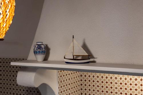 a toy boat sitting on a shelf with a vase at La casa del Geologo in Stromboli