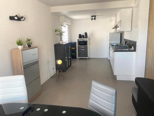 - une petite cuisine avec des placards blancs, une table et des chaises dans l'établissement Grand T2 centre-ville, calme, lumineux et spacieux, 1 chambre, 1 à 5 pers, climatisation, wifi, parking libre et gratuit, à Lorient