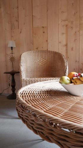 a wicker chair with a bowl of fruit on it at Haixpia, Les Chambres d'Hôtes in Hasparren