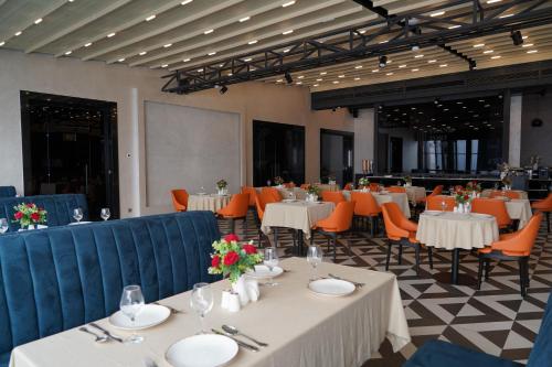a dining room with white tables and orange chairs at FRANKFORT Expo Hotel in Tashkent