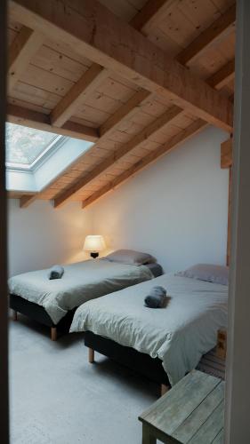 two beds in a room with wooden ceilings at Haixpia, Les Chambres d'Hôtes in Hasparren