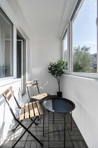 two chairs and a table in a room with windows at GoldenHugo rooms in Vilnius