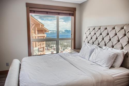 a bedroom with a bed and a large window at Stonegate Resort Unit B208 in Big White