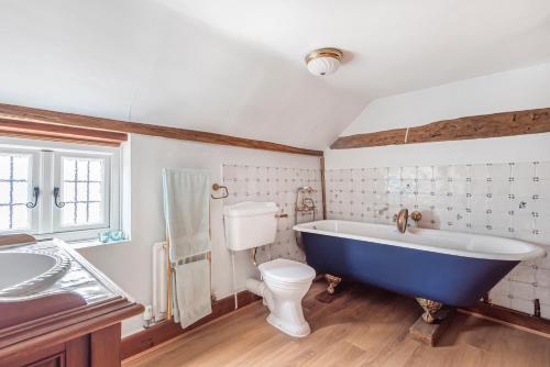 a bathroom with a blue tub and a toilet at Huge Cottage for Sophisticated Hen Party and Large Groups in Hurst