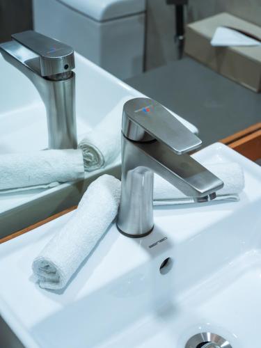 a bathroom sink with a faucet and towels on it at Araamu Hotels Maldives at Dhiffushi in Dhiffushi