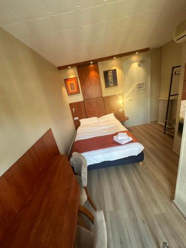 a small bedroom with a bed and a table at Hôtel Victoria in Reims