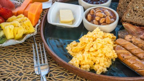 a plate of scrambled eggs and other food on a table at Elite Atoll Serviced Apartments Phuket in Rawai Beach