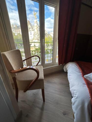 a bedroom with a chair and a large window at Hôtel Victoria in Reims