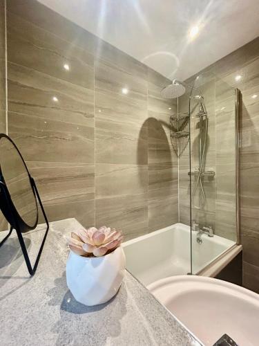 a bathroom with a tub and a vase on a counter at Modern 2 Bed Apartment With Free Parking And Netflix in Dawley