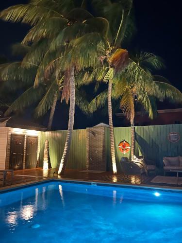 a swimming pool with palm trees in front of a house at The Palms in Belize City
