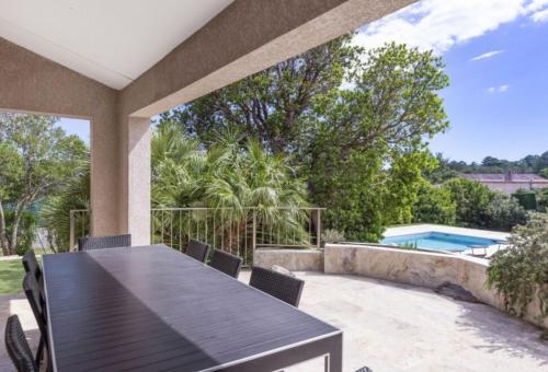 un patio avec une table et des chaises et une piscine dans l'établissement VILLA Pauline, à Porto-Vecchio