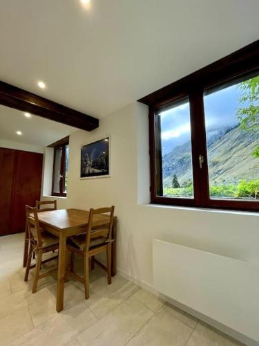 une salle à manger avec une table, des chaises et des fenêtres dans l'établissement Grand studio Champagny-le-Haut, à Champagny-en-Vanoise