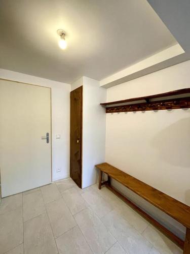 une pièce vide avec un banc en bois et une porte dans l'établissement Grand studio Champagny-le-Haut, à Champagny-en-Vanoise