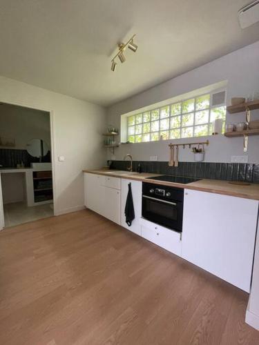 La cuisine est équipée de placards blancs et d'un four avec plaques de cuisson noires. dans l'établissement Opale plage, à Dunkerque