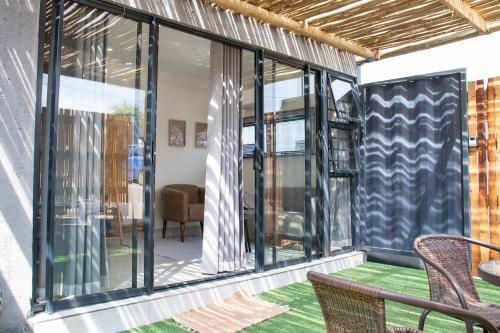 a screened porch with glass doors and chairs at Cozy Box Haus in Graskop