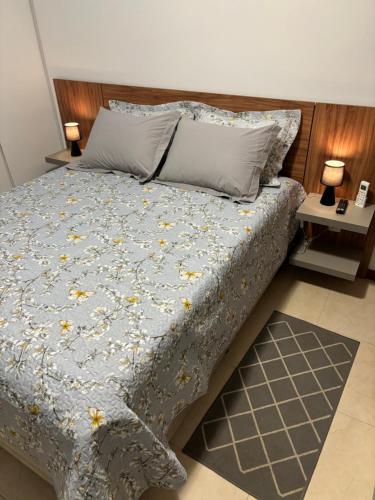 una camera da letto con un letto con un piumone blu e due tavoli di Apartamento em Itaipava a Petrópolis