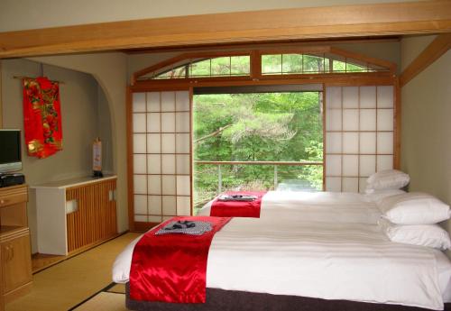 a bedroom with a large bed and a large window at White Horse Hotel in Hakuba