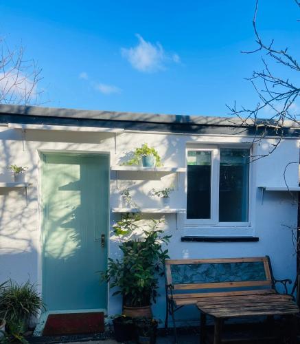 a white house with a green door and a bench at Zen Garden Hideaway. Close to Harry Potter&trains. in Watford