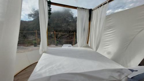 a white bed in a room with a window at Glamping Burbuja Los Almendros in Málaga