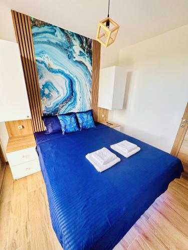 a blue bed with two towels on top of it at Indigo Royale apartman Borovi in Divčibare
