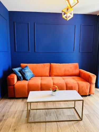an orange couch in a blue room with a coffee table at Indigo Royale apartman Borovi in Divčibare