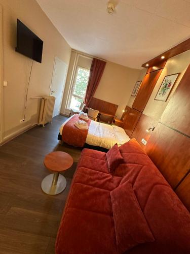 a hotel room with two beds and a television at Hôtel Victoria in Reims