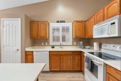 a kitchen with wooden cabinets and white appliances at Sunny Home with Backyard Oasis in San Tan Valley! in Queen Creek