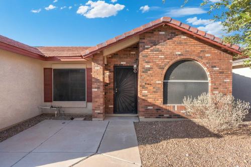 a brick house with a black door and a driveway at Sunny Home with Backyard Oasis in San Tan Valley! in Queen Creek