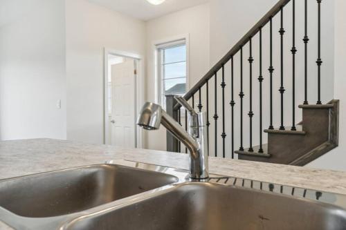 una encimera con fregadero y una escalera en A Brand New 4BR Townhouse in Thorold Retreat, en Thorold