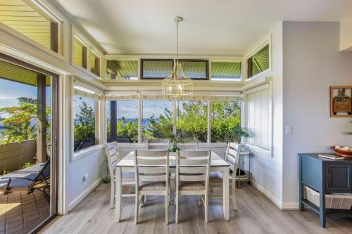 a dining room with a table and chairs and windows at Gorgeous Kapalua Home with Views in Kahana