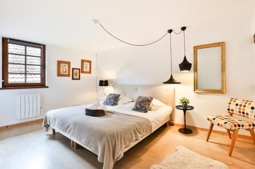 a bedroom with a bed and a mirror and a chair at Au pied des remparts à Eguisheim in Eguisheim