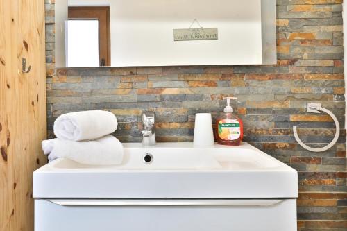 a white sink in a bathroom with a brick wall at Au pied des remparts à Eguisheim in Eguisheim