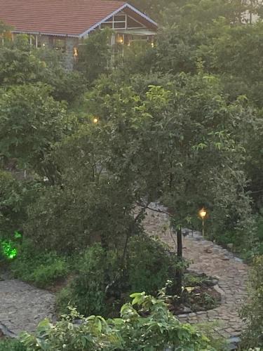 a tree in a garden with a house in the background at Eshi Resorts and Restaurant - Bhimashankars Jungle Luxury Resort in Taleghar