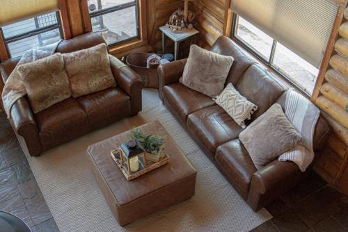 a living room with a leather couch and a table at Charming Log AFrame in Pine in Pine