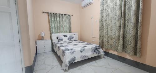 a small bedroom with a bed and a dresser at Palm Breeze Villa JM in Lucea