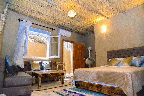 a bedroom with a bed and a chair and a window at Tangomar club kech in Marrakech
