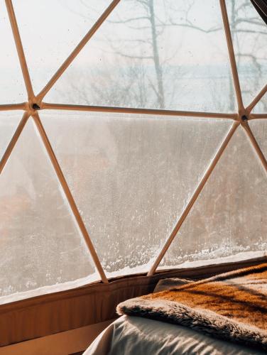 a glass igloo with a bed in front of a window at Dômes Charlevoix in Petite-Rivière-Saint-François