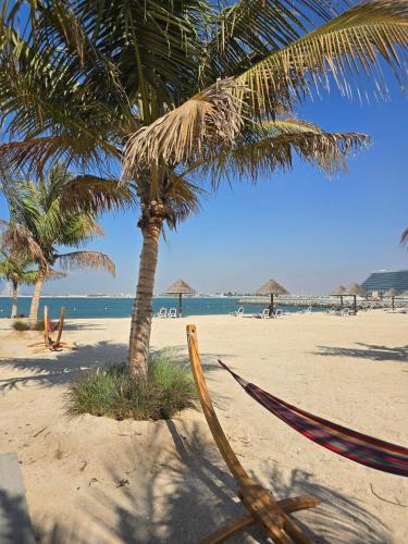 a hammock and a palm tree on a beach at Seaview Escape Family Two-Room Apartment with Seaview in Ras al Khaimah