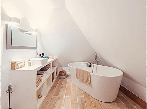une salle de bain blanche avec une baignoire et un lavabo dans l'établissement Maison au bord de la Seine, à Vatteville
